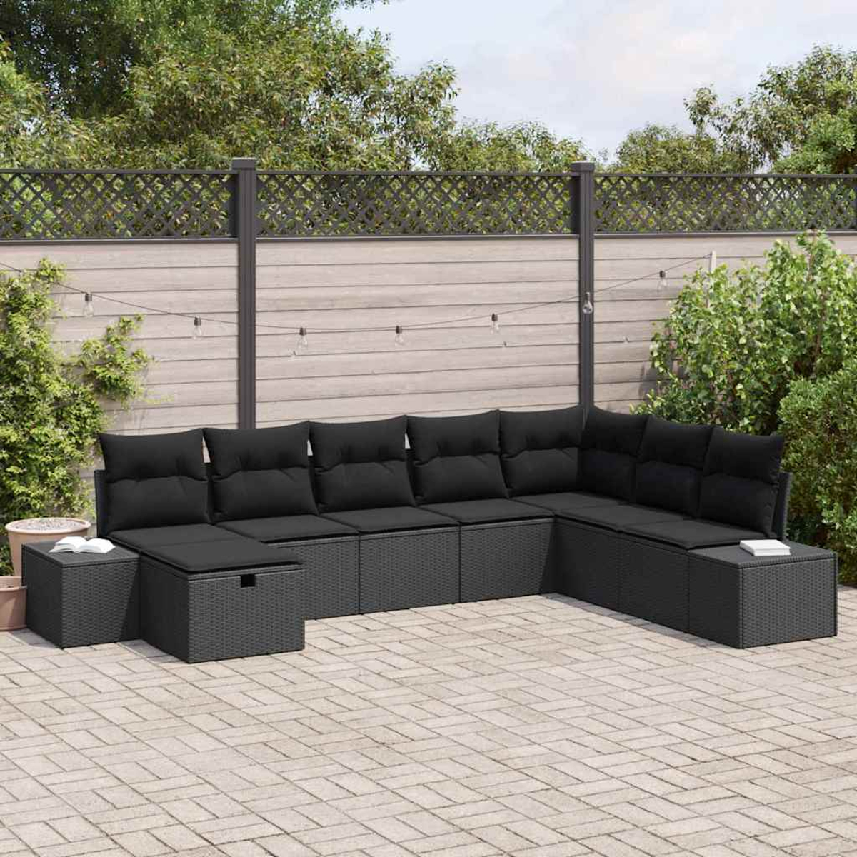 Ein Ecksofa im Freien mit schwarzen Kissen. Die Kulisse ist eine Terrasse mit Holzzaun und Pflanzen im Hintergrund.