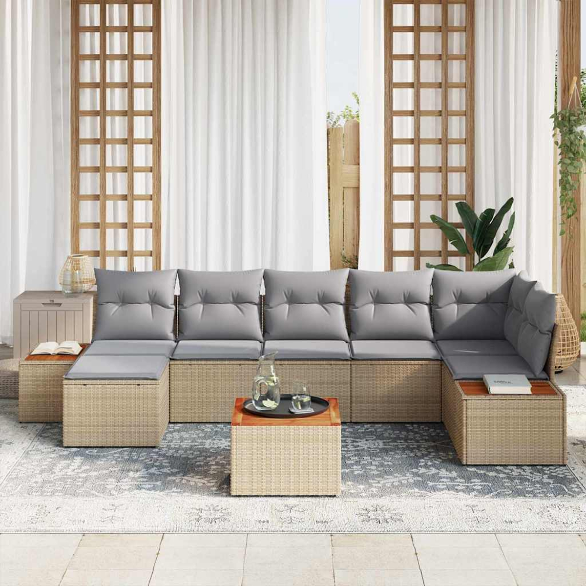 Outdoor-Ecksofa mit grauen Kissen und Rattansockel. Couchtisch mit Tablett, Glas und Krug. Weiße Vorhänge und Holzgitter.