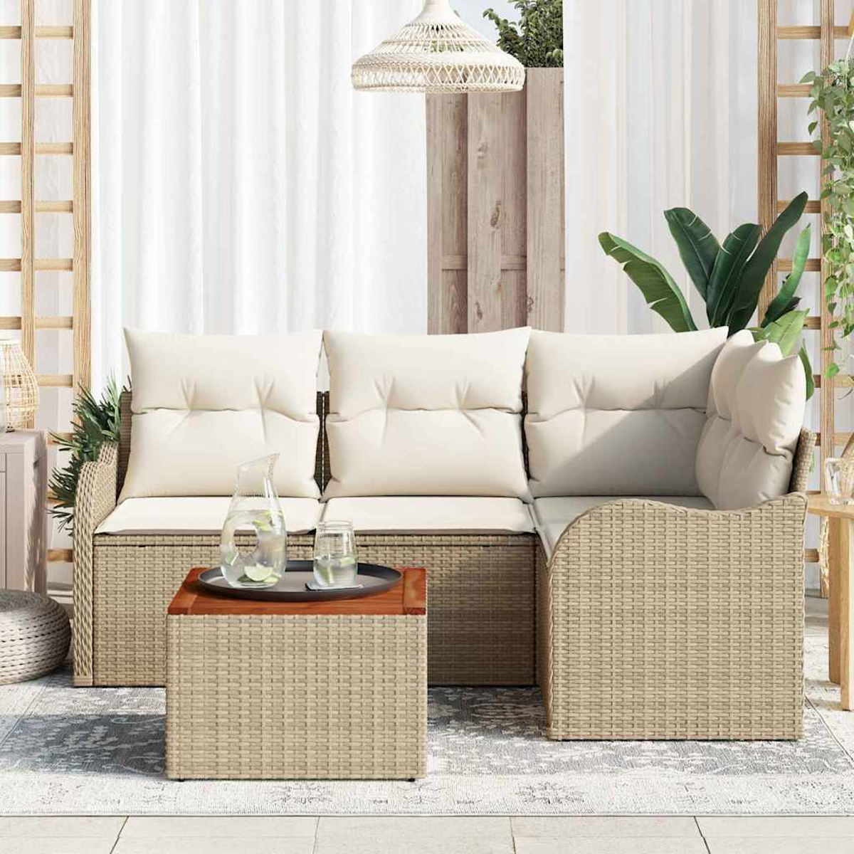 Outdoor-Sitzbereich mit Korbmöbeln, Couchtisch und weißen Kissen. Enthält Wasserkrug und Glas. Weiße Vorhänge im Hintergrund.