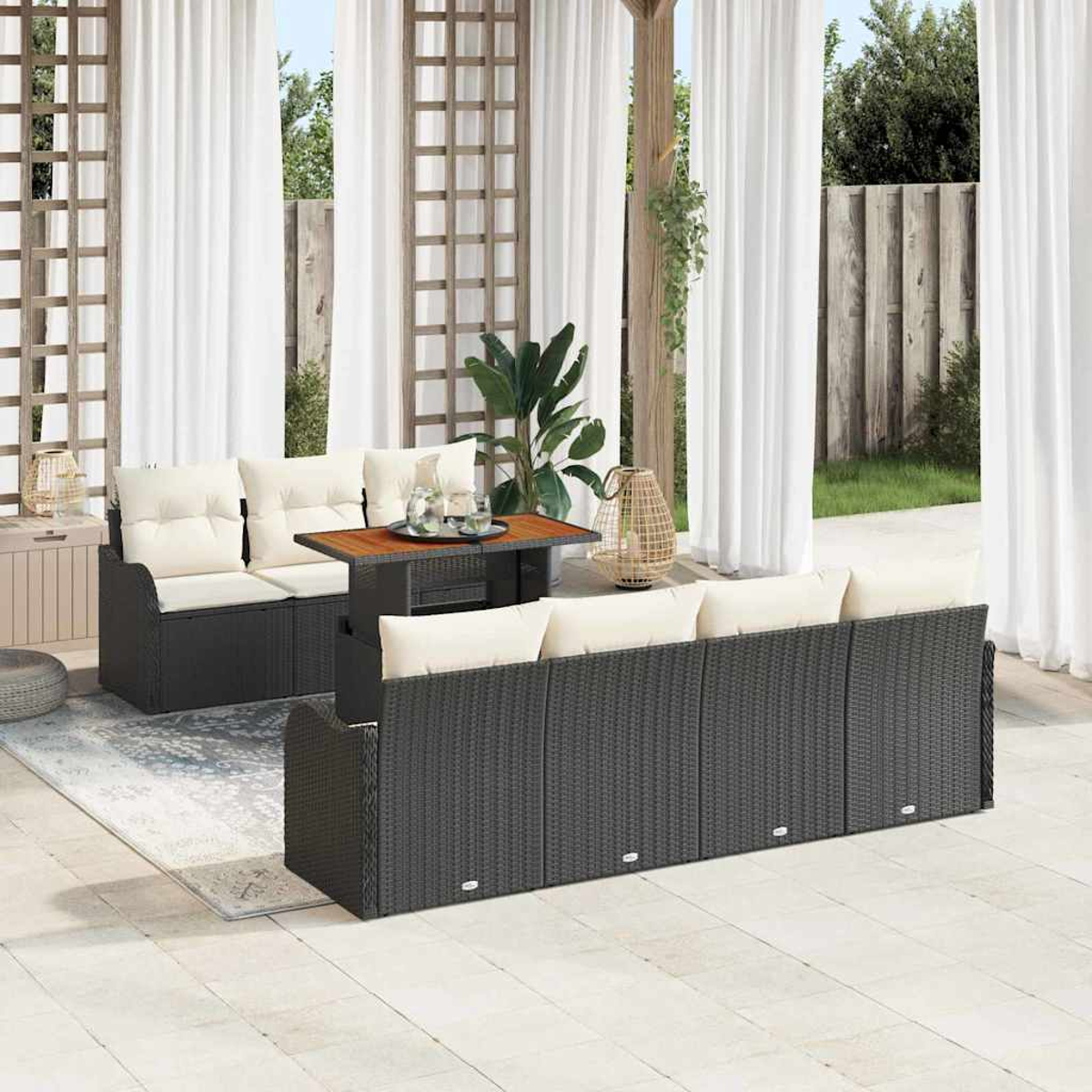 Terrassenset mit zwei Sofas, einem Tisch und weißen Kissen. Weiße Vorhänge und Grün im Hintergrund. Das Set ist dunkelgrau.