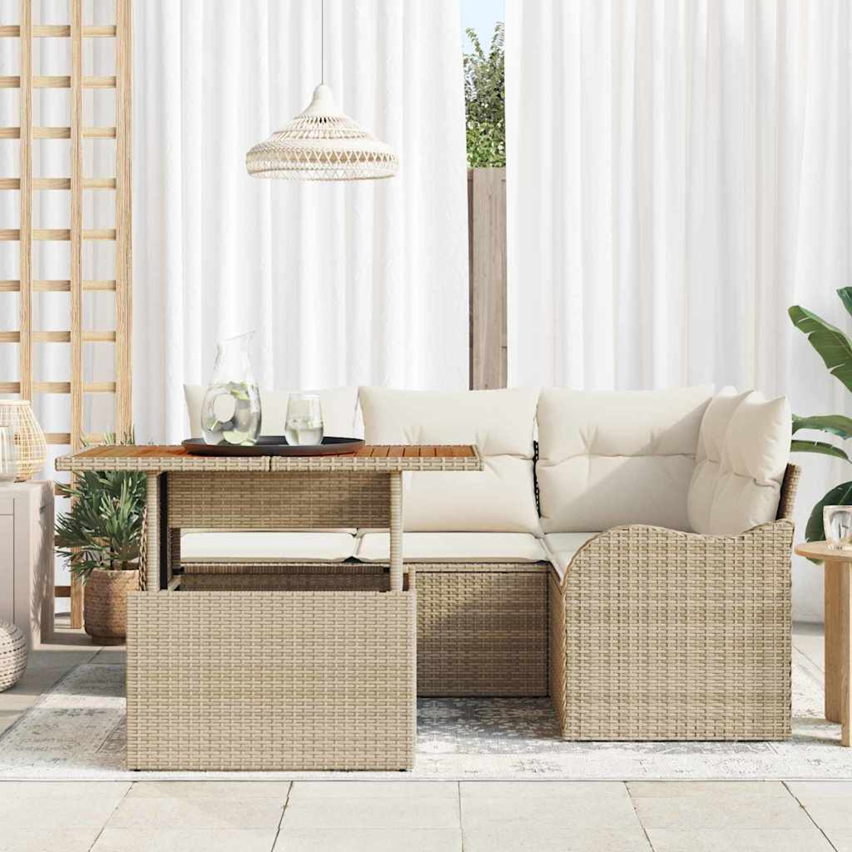 Outdoor-Set mit Korbmöbeln. Ein Tisch mit einem Tablett mit Getränken, ein Sofa mit Kissen und weiße Vorhänge im Hintergrund.