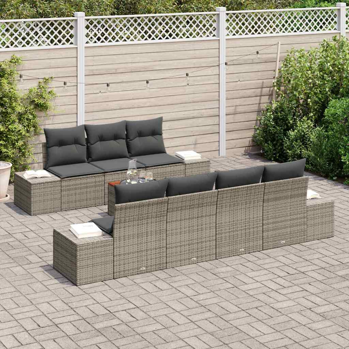Outdoor-Sitzgruppe auf einer Ziegelsteinterrasse. Graue Korbmöbel mit grauen Kissen. Weißer Zaun und Grün im Hintergrund.