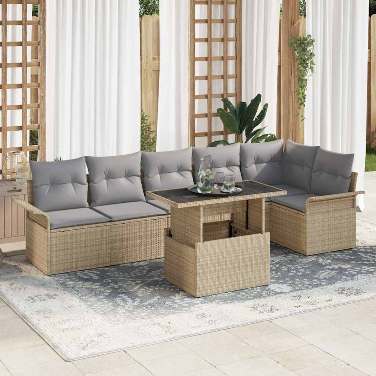 Gartenmöbel-Set aus Weide mit grauen Kissen, einem Tisch und weißen Vorhängen. Auf dem Tisch stehen eine Kanne und Gläser.