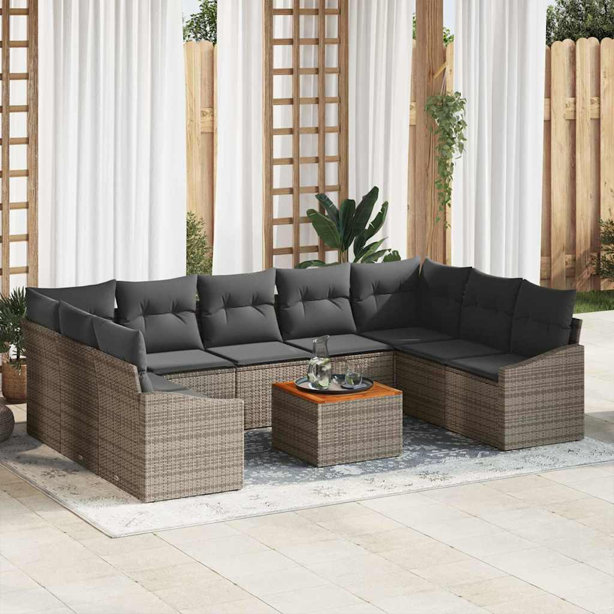 Outdoor-Ecksofa mit grauen Kissen und einem Couchtisch. Weiße Vorhänge und Holzzaun im Hintergrund. Pflanzen im Hintergrund.