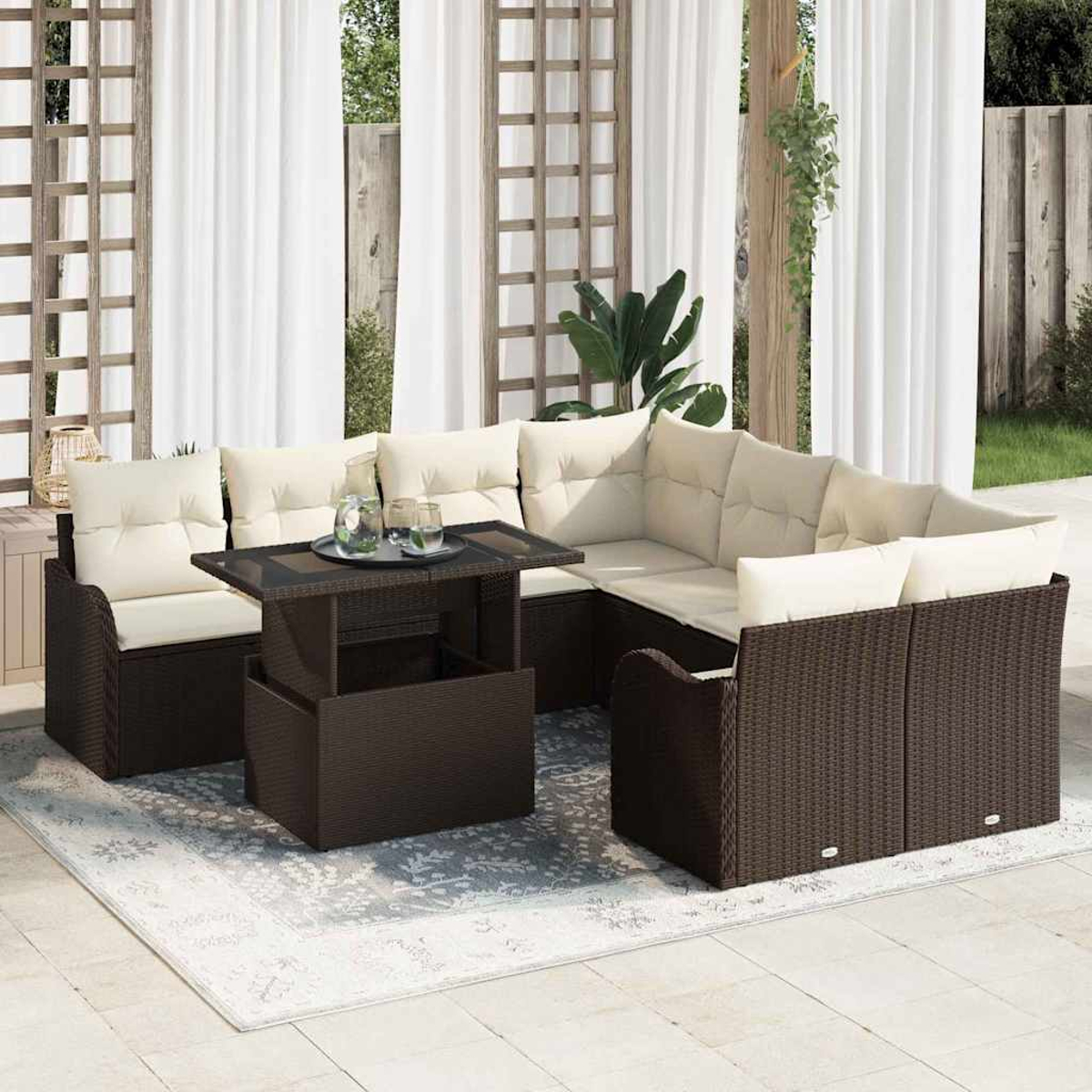 Garten-Sitzgruppe mit braunen Korbmöbeln, beigen Kissen, einem Tisch mit Glasplatte und einem Teppich. Weiße Vorhänge und ein Holzgitter im Hintergrund.