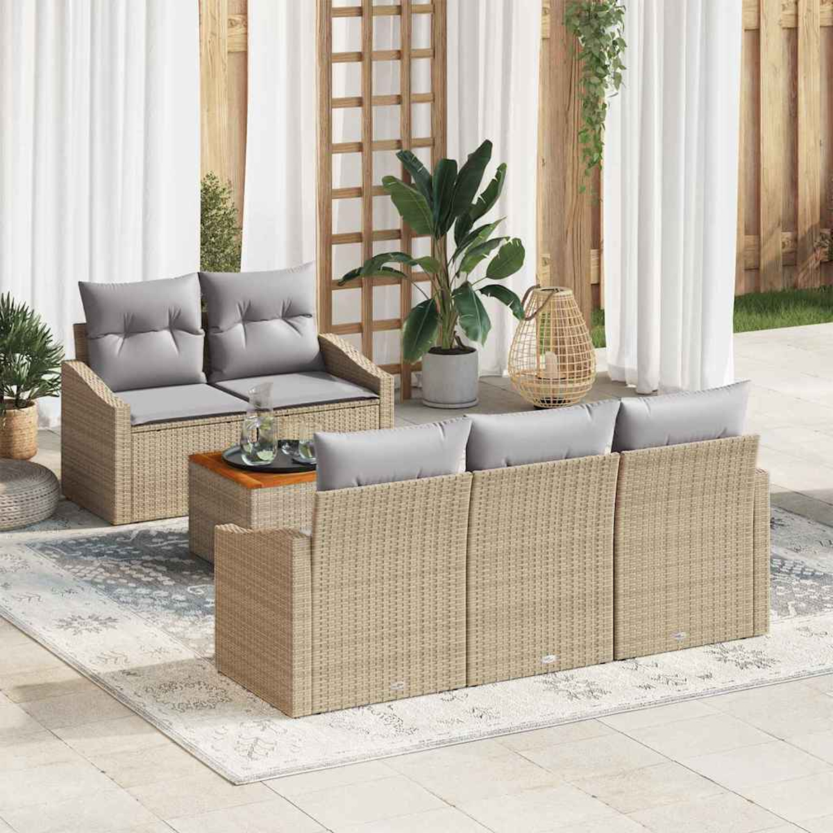 Gartenmöbel-Set mit grauen Kissen, auf einer Terrasse mit Teppich, Pflanzen und Vorhängen.