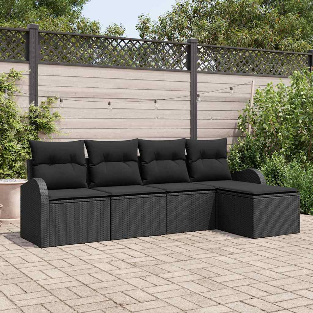 Ein schwarzes Outdoor-Ecksofa mit Kissen steht auf einer Ziegelterrasse. Im Hintergrund befinden sich ein Holzzaun und Grün.