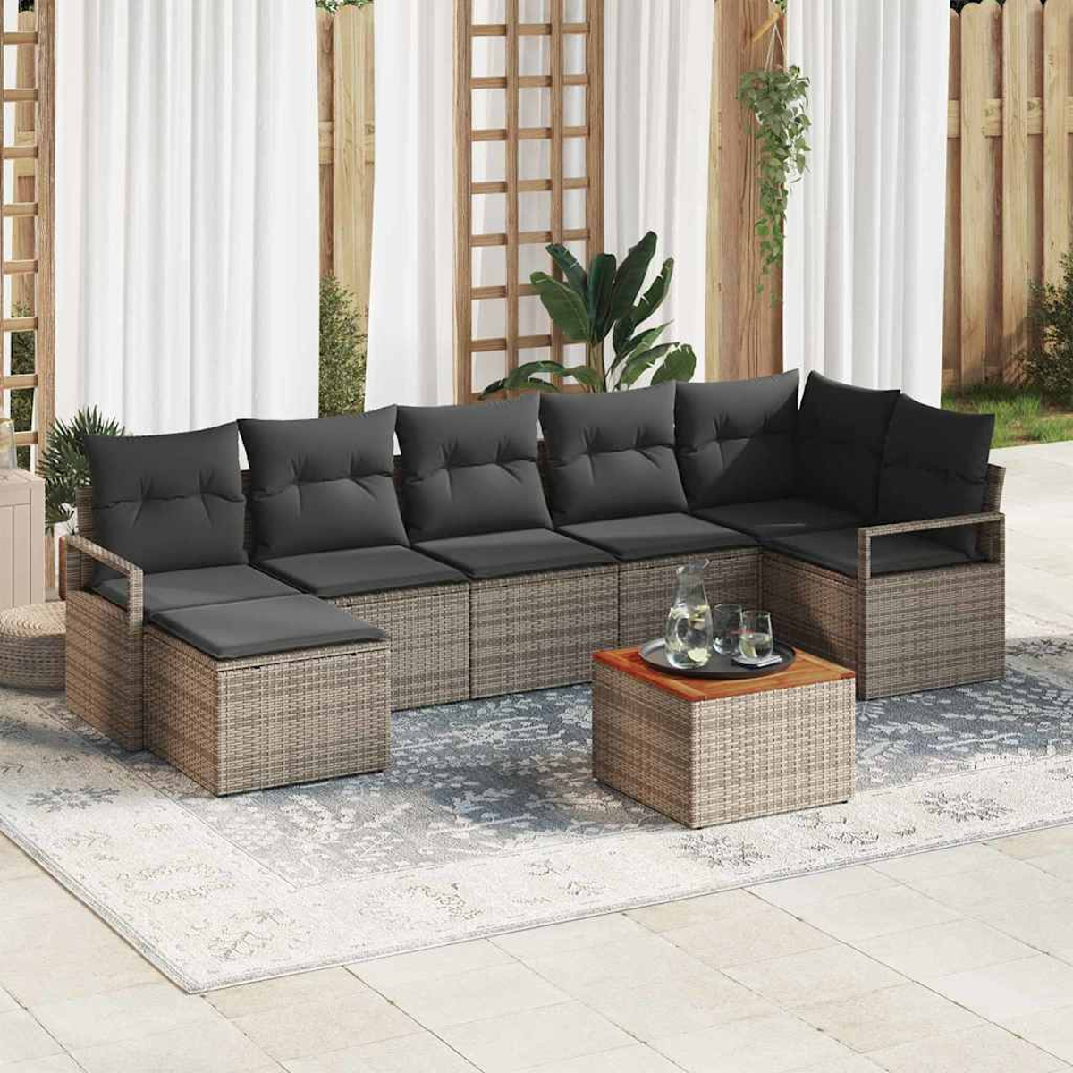 Outdoor-Ecksofa mit grauen Kissen und einem Holztisch mit Gläsern. Weiße Vorhänge und ein Holzzaun im Hintergrund.