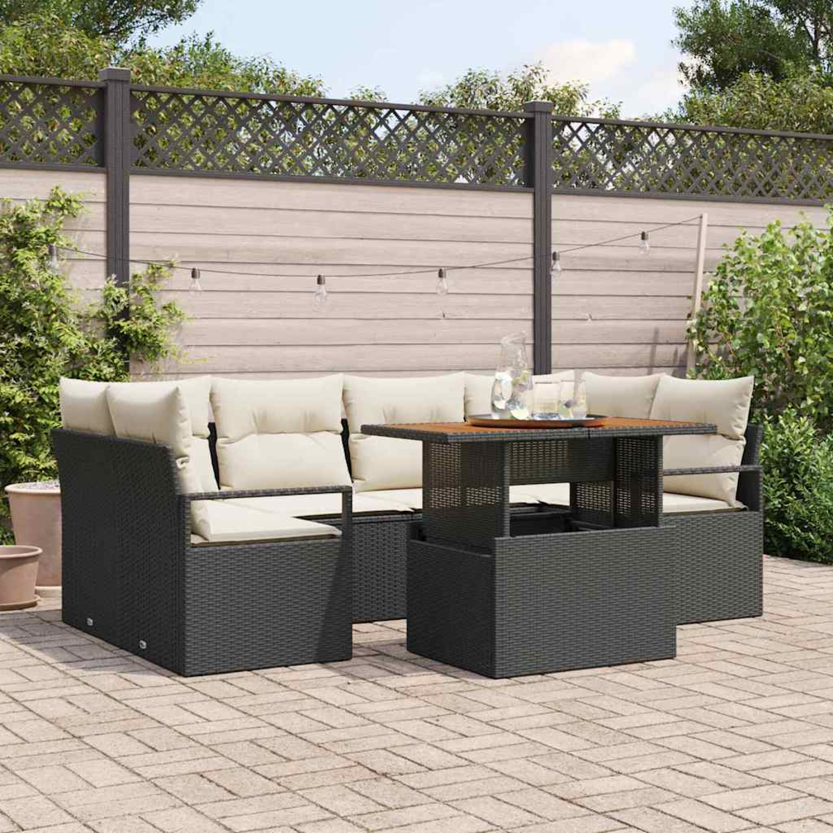 Garten-Terrassenset mit schwarzer Korbmöbeln und beigen Kissen. Ein Holztisch mit einem Glas Wasser. Garten im Hintergrund.
