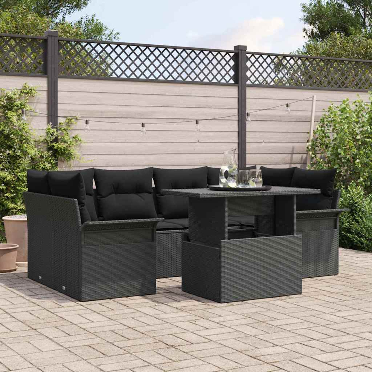 Graues Outdoor-Ecksofa mit schwarzen Kissen, Tisch mit Tablett und Holzzaun im Hintergrund.