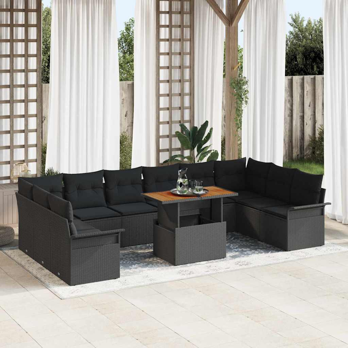 Terrassenset im Freien mit schwarzen Kissen und einem Tisch mit Hubfunktion. Weiße Vorhänge und Holzpergola im Hintergrund.