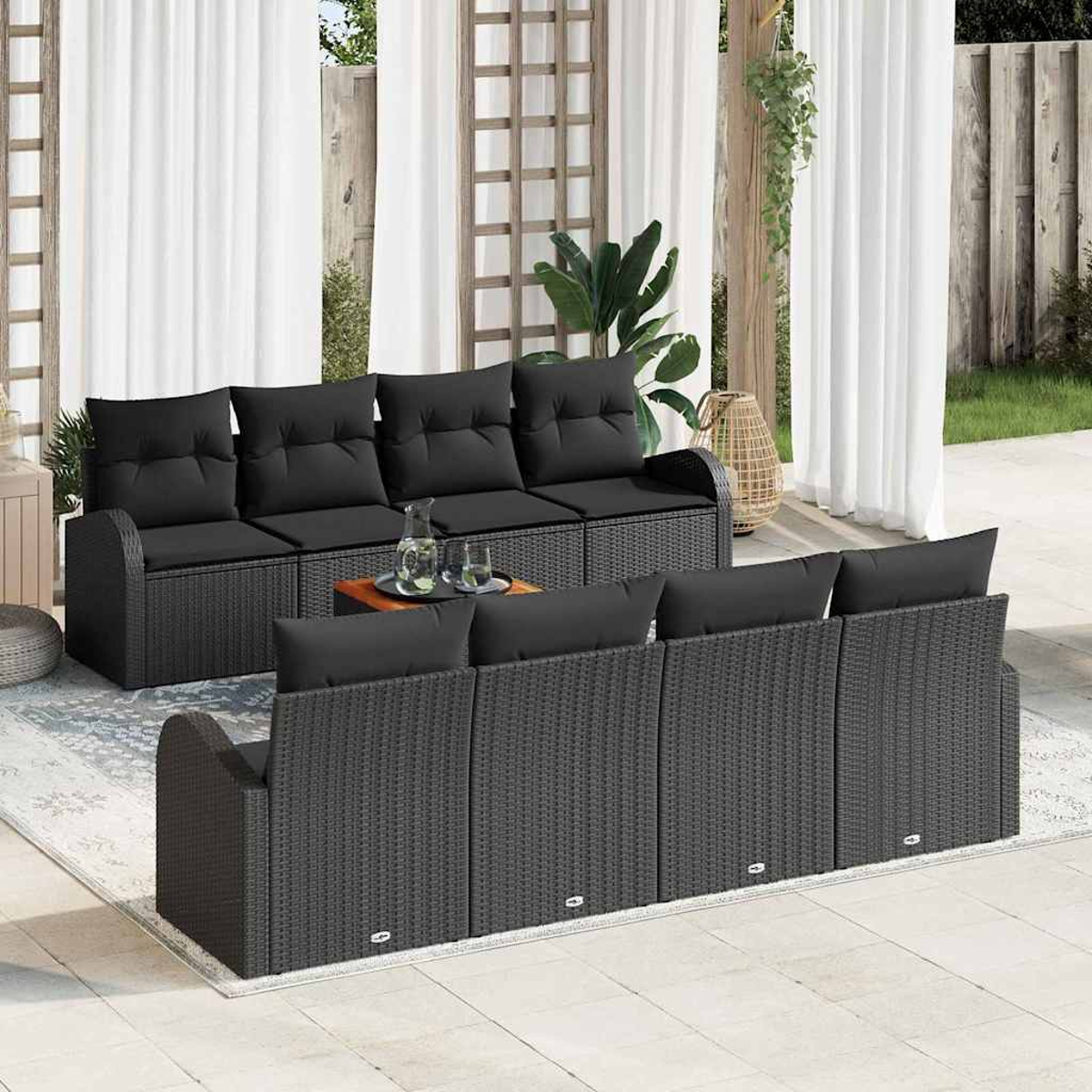 Gartenmöbel-Set: schwarze Korbsessel, schwarze Kissen, Holztisch, weiße Vorhänge, Teppich und Pflanzen.