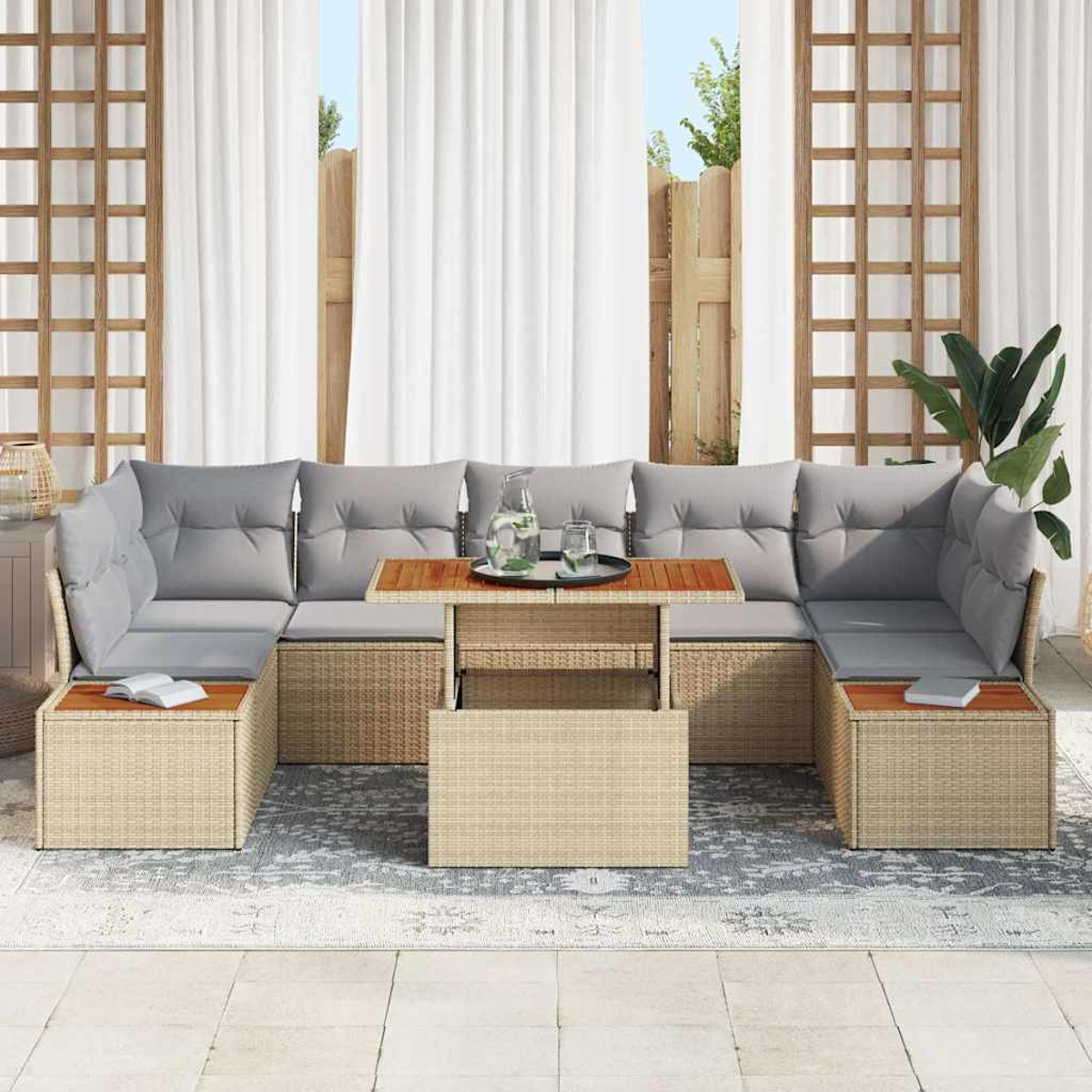 Outdoor-Sitzgruppe aus Korbgeflecht mit grauen Kissen und Holztisch. Weiße Vorhänge und ein Spalier im Hintergrund.