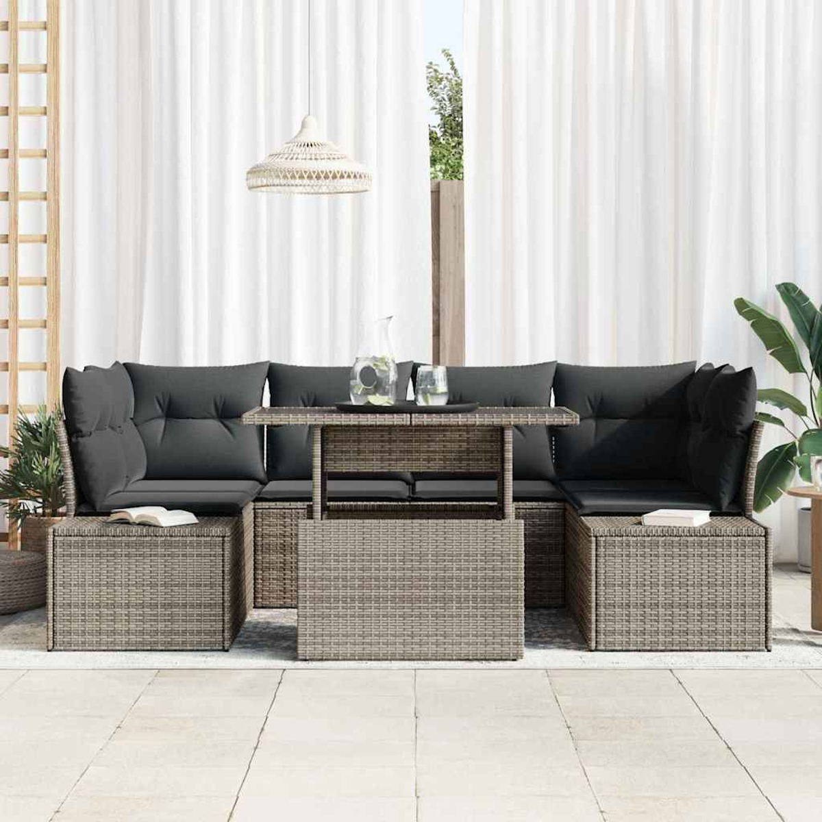 Rattan-Gartenset mit grauen Kissen, einem Tisch mit Getränken und weißen Vorhängen im Hintergrund.