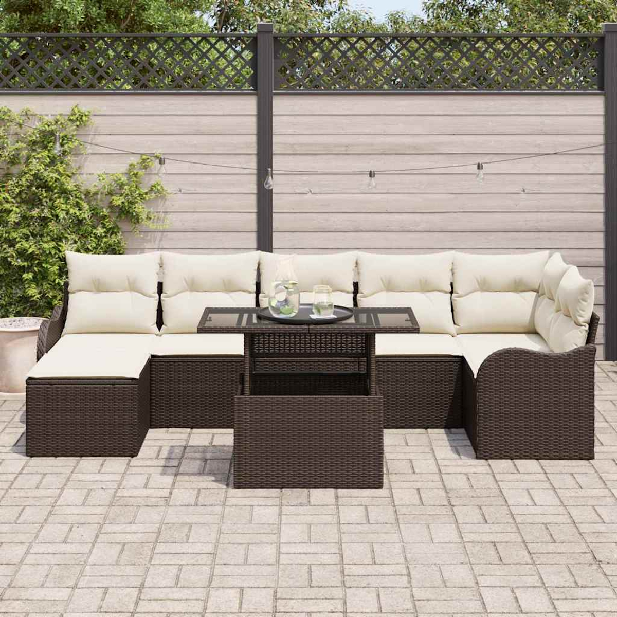 Gartenmöbel-Set: braunes Korbsessel-Sofa mit cremefarbenen Kissen, Tisch mit Glasplatte, auf einer Ziegelpflasterung, vor einem Zaun.