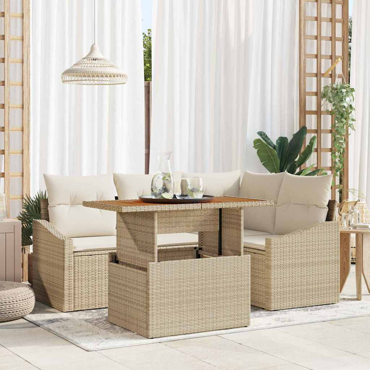 Juego de muebles de mimbre para exterior con mesa, sofá y sillones. Cortinas blancas y una lámpara colgante al fondo.