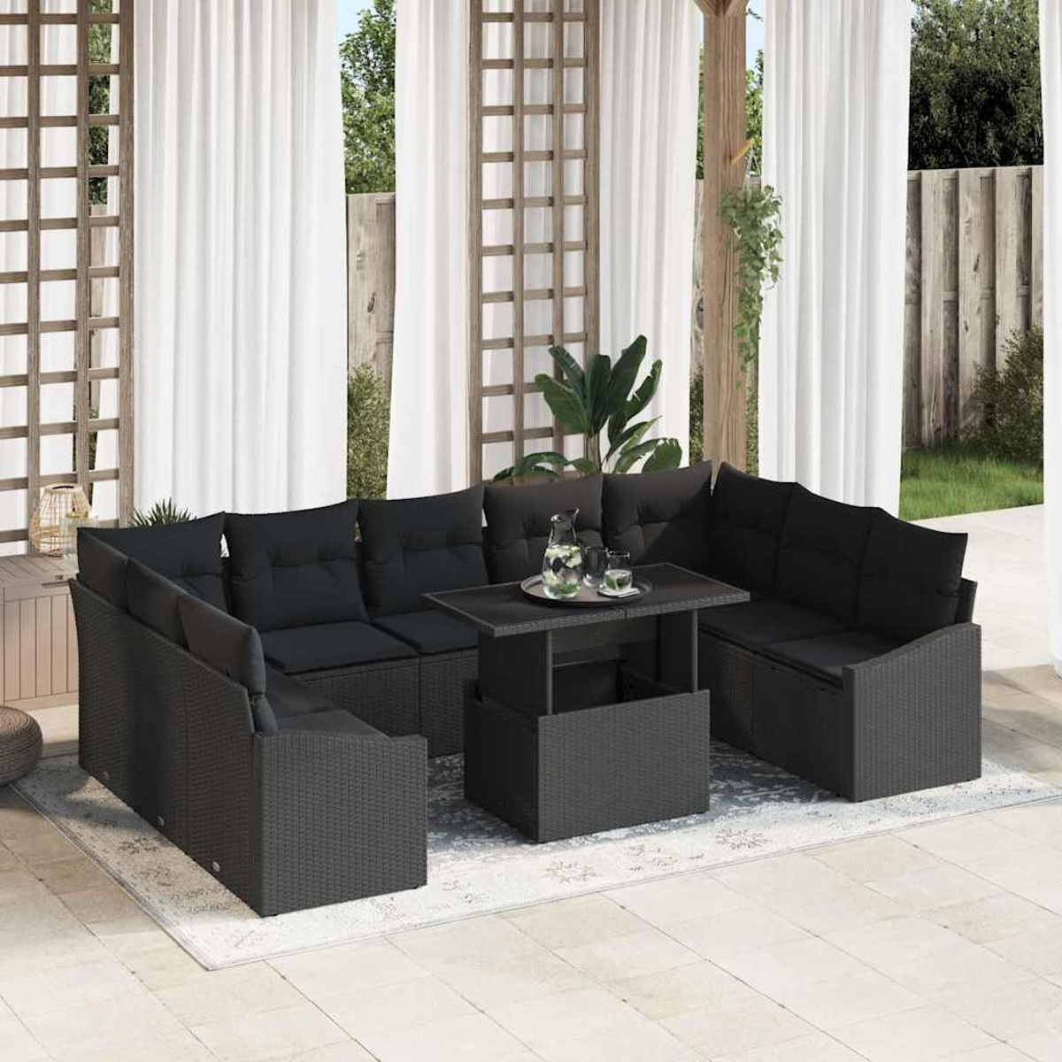 Schwarzes Rattan-Sofa-Set im Freien mit Kissen und einem Tisch. Hintergrund mit weißen Vorhängen und Spalieren. Tisch mit Gläsern und Krug.