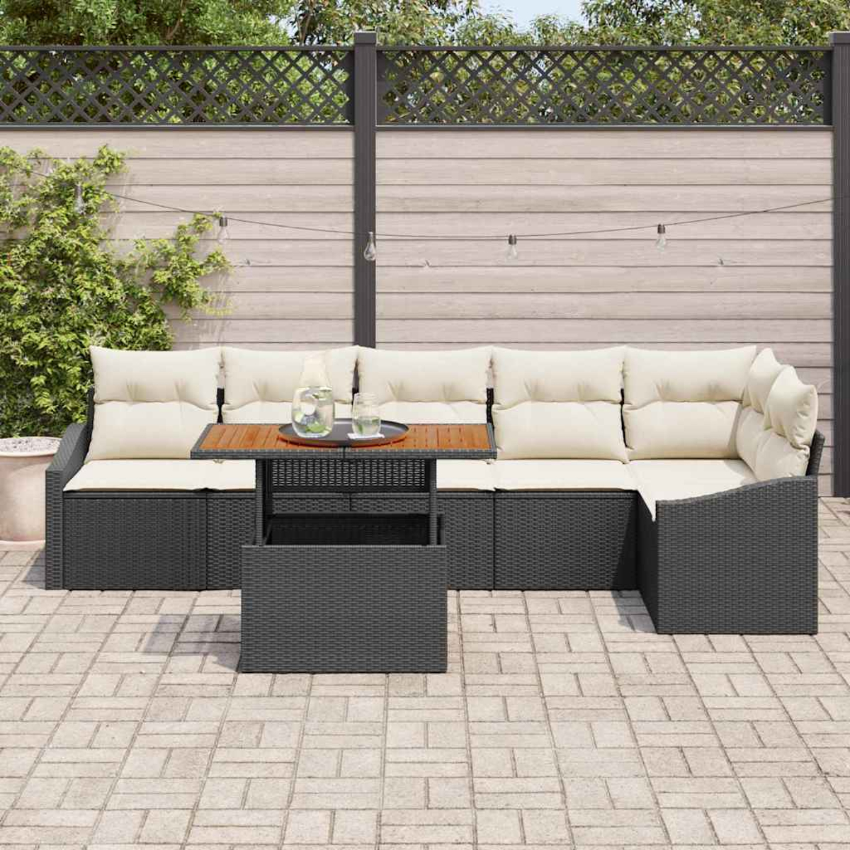 Sofá seccional al aire libre con cojines beige, una mesa de madera y una caja de almacenamiento a juego. Contra una valla de madera y vegetación.