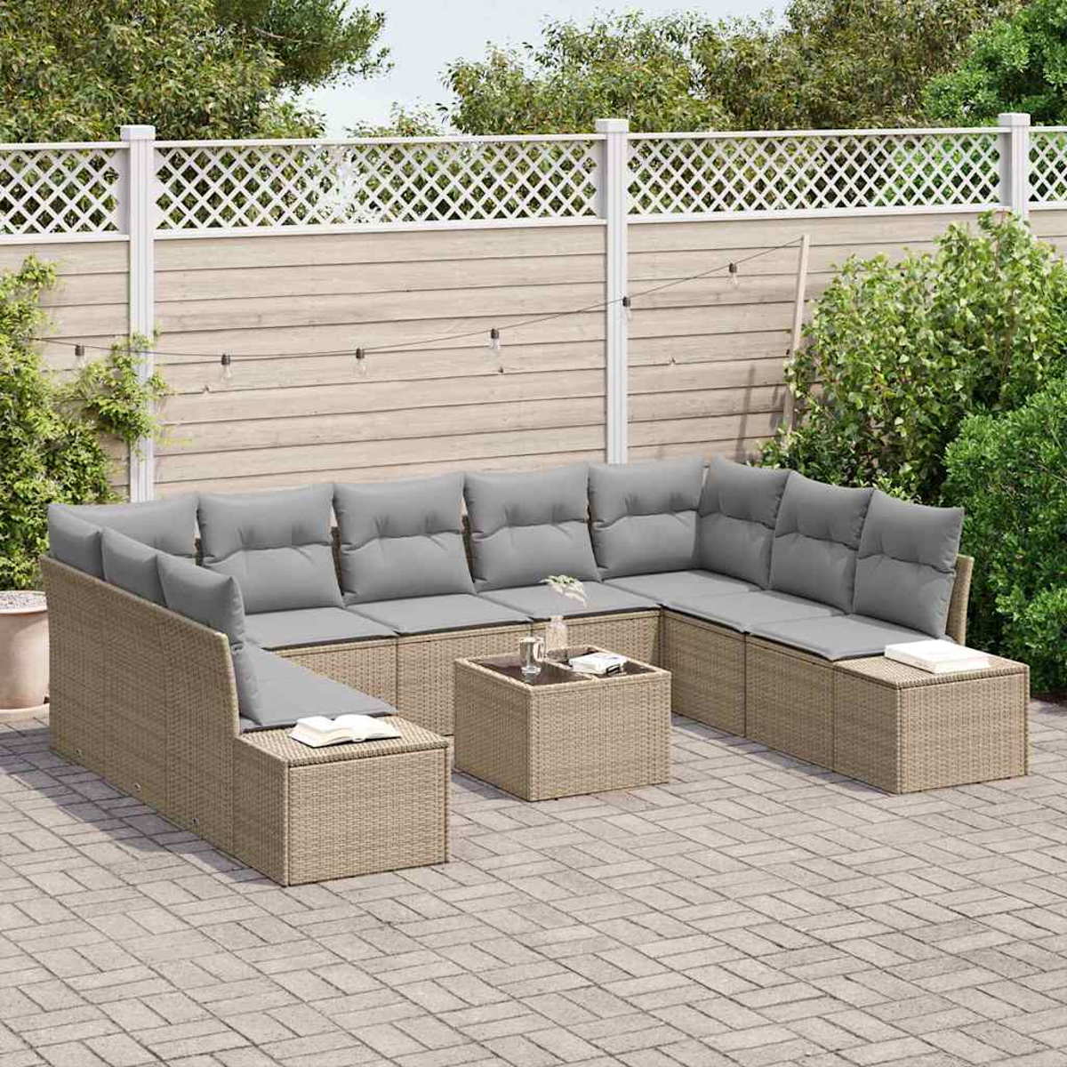 Ein Ecksofa mit grauen Kissen im Freien steht auf einer Terrasse. Ein kleiner Tisch und ein Zaun sind im Hintergrund.