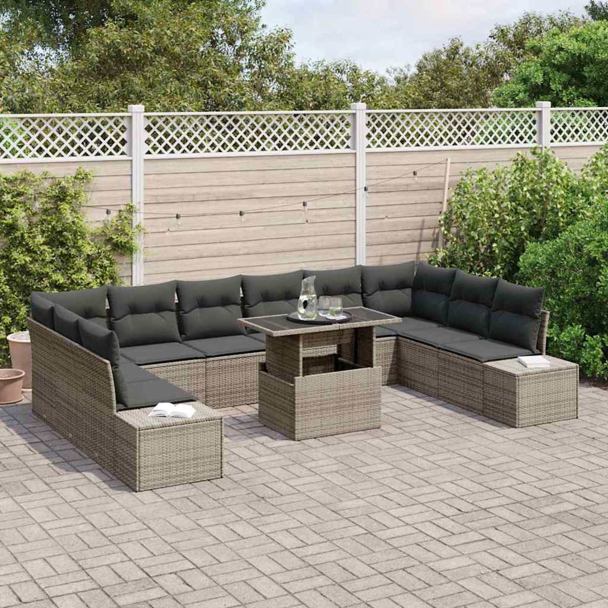 Outdoor-Ecksofa mit grauen Kissen und einem Tisch mit Hubfunktion. Im Hintergrund ein weißer Zaun und Grün.