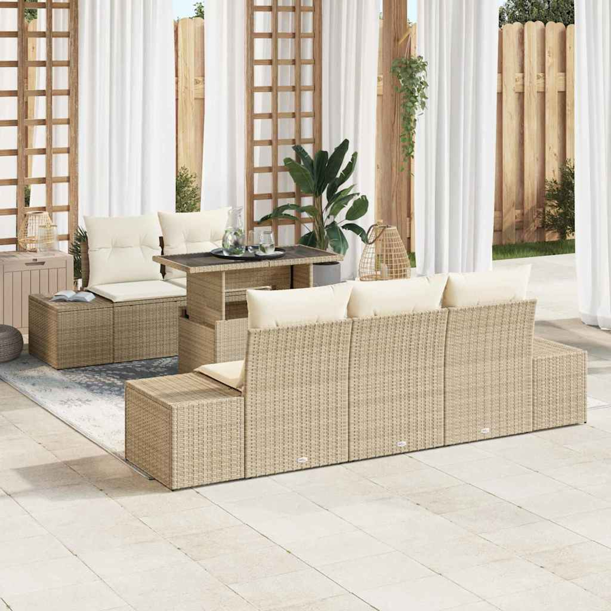 Gartenmöbel-Set aus Korbgeflecht. Es zeigt ein beiges Sofa, Tisch und Ottomanen vor weißem Vorhang und Holzzaun.