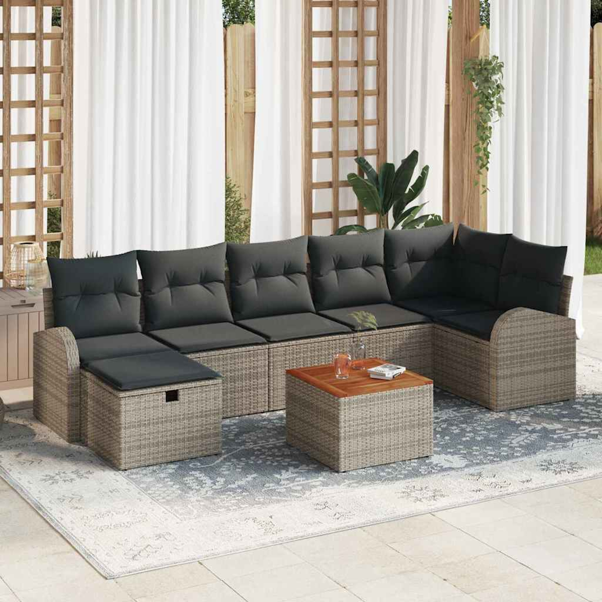 Ein Ecksofa im Freien mit grauen Kissen und einem kleinen Holztisch. Das Sofa steht auf einem gemusterten Teppich, Vorhänge im Hintergrund.