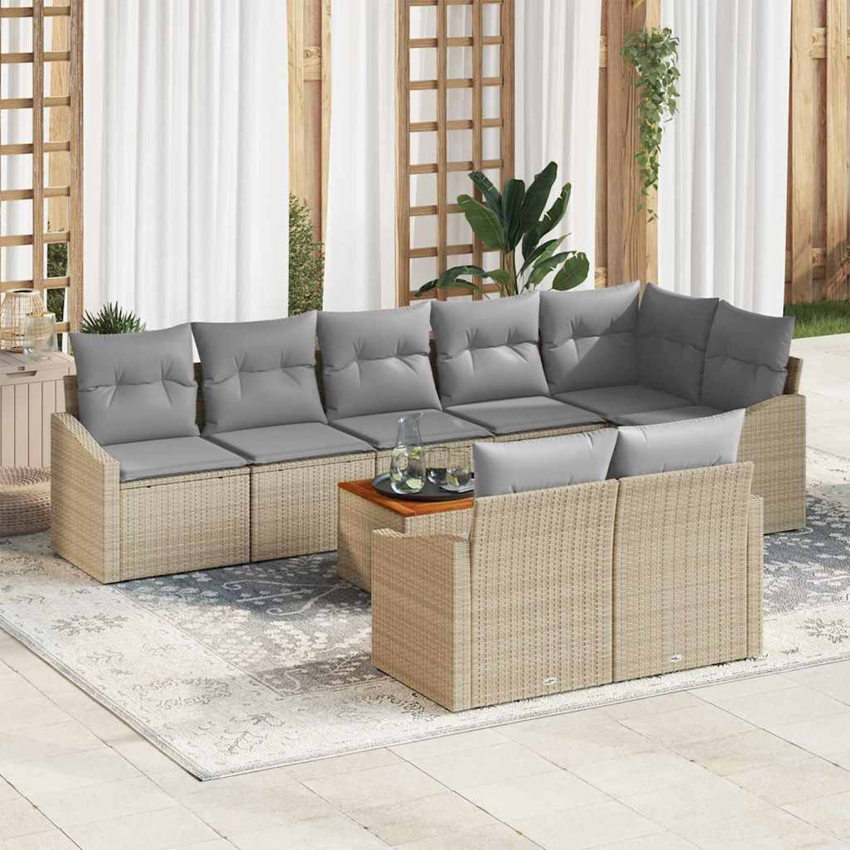 Outdoor-Ecksofa mit grauen Kissen auf einem gemusterten Teppich. Ein kleiner Holztisch hält Gläser. Weiße Vorhänge und Holzpaneele sind im Hintergrund.