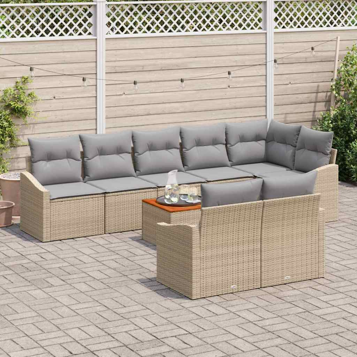 Outdoor-Sitzbereich mit beigem Korbsessel, grauen Kissen und einem kleinen Holztisch. Gepflasterte Terrasse und Holzzaun.