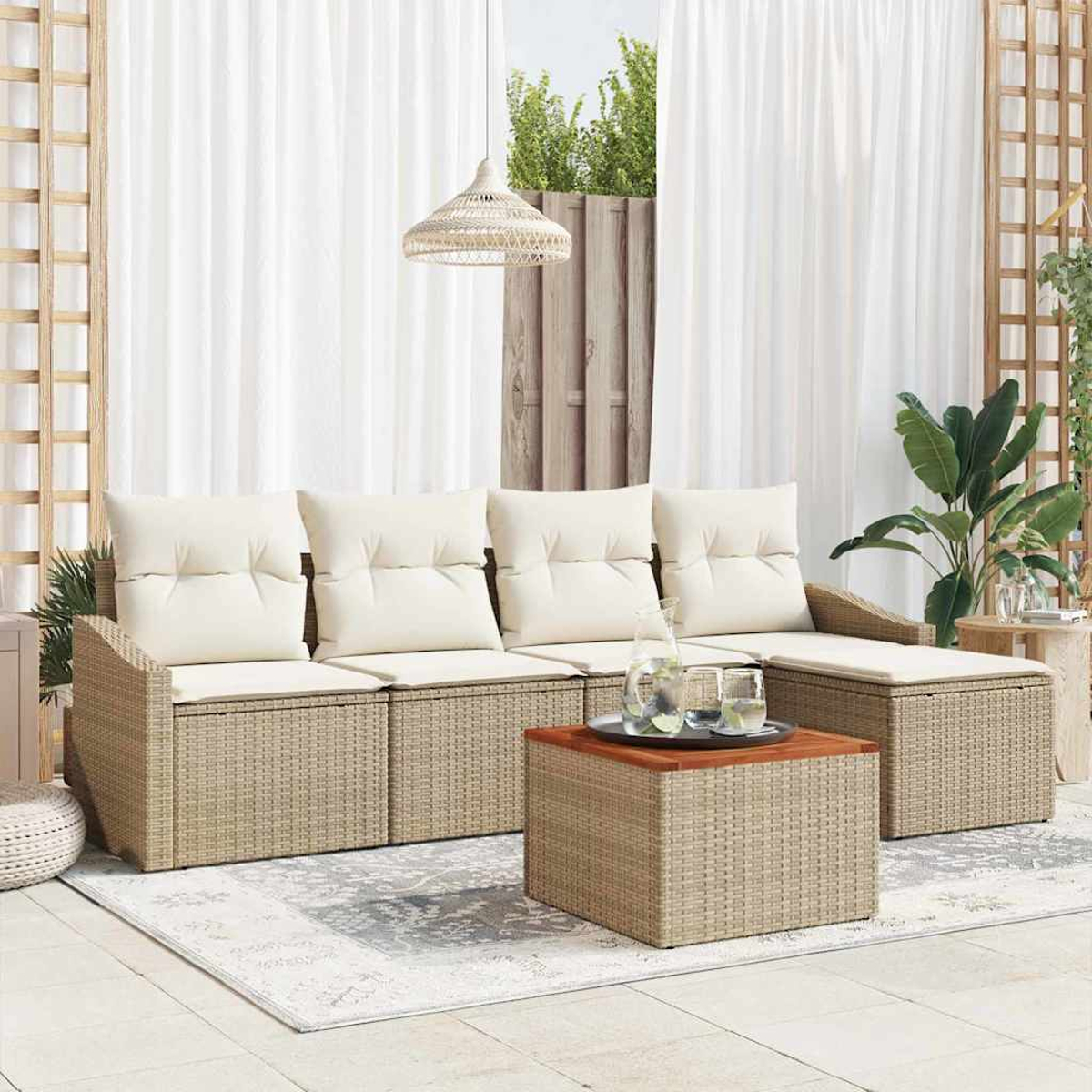 Outdoor-Sitzbereich mit beigen Kissen, Korbmöbeln und einem Holztisch. Weiße Vorhänge und Pflanzen ergänzen die Szene.