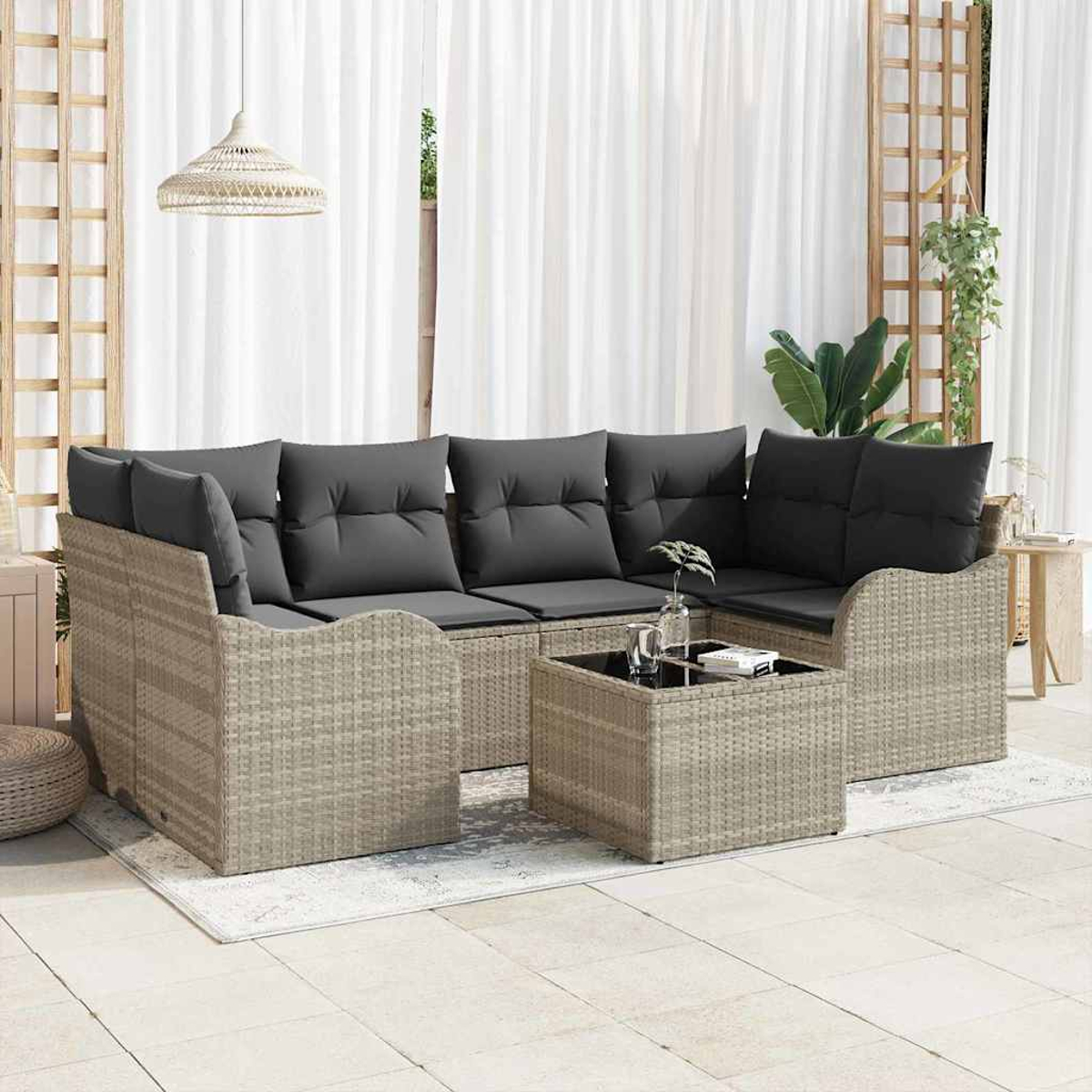 Garten-Sitzgruppe mit grauen Kissen. Davor steht ein quadratischer Couchtisch. Weiße Vorhänge und eine Hängeleuchte sind im Hintergrund.