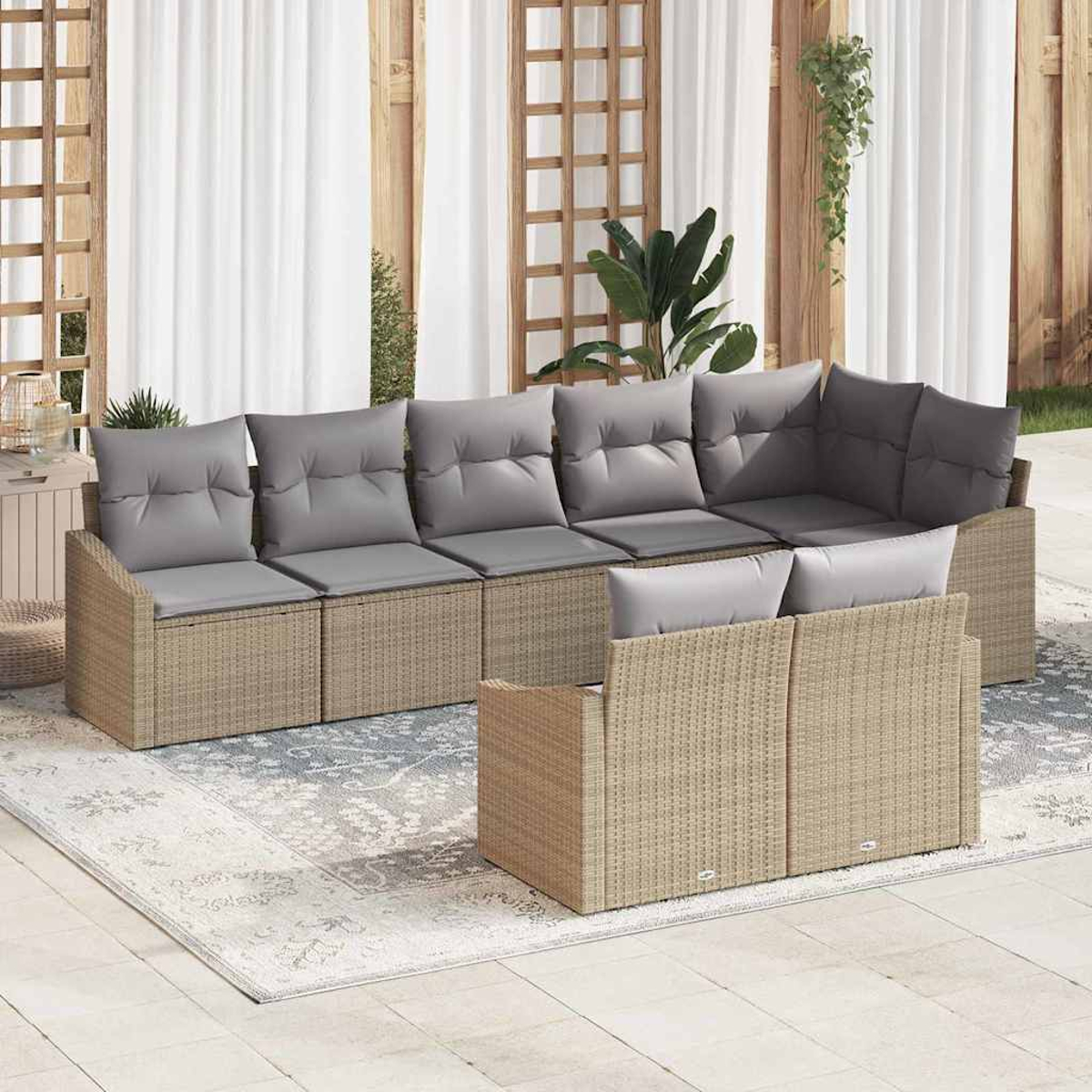 Outdoor-Korbsofa mit grauen Kissen. Es steht auf einem Teppich, mit hölzernem Hintergrund, Vorhängen und Pflanzen.