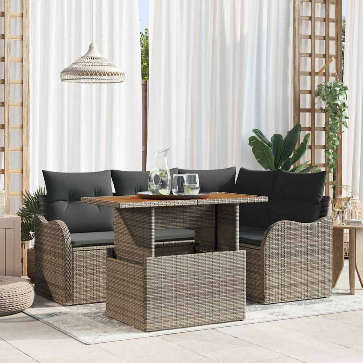 Juego de muebles de patio: una mesa con bebidas, dos sofás con cojines grises y cortinas blancas al fondo.