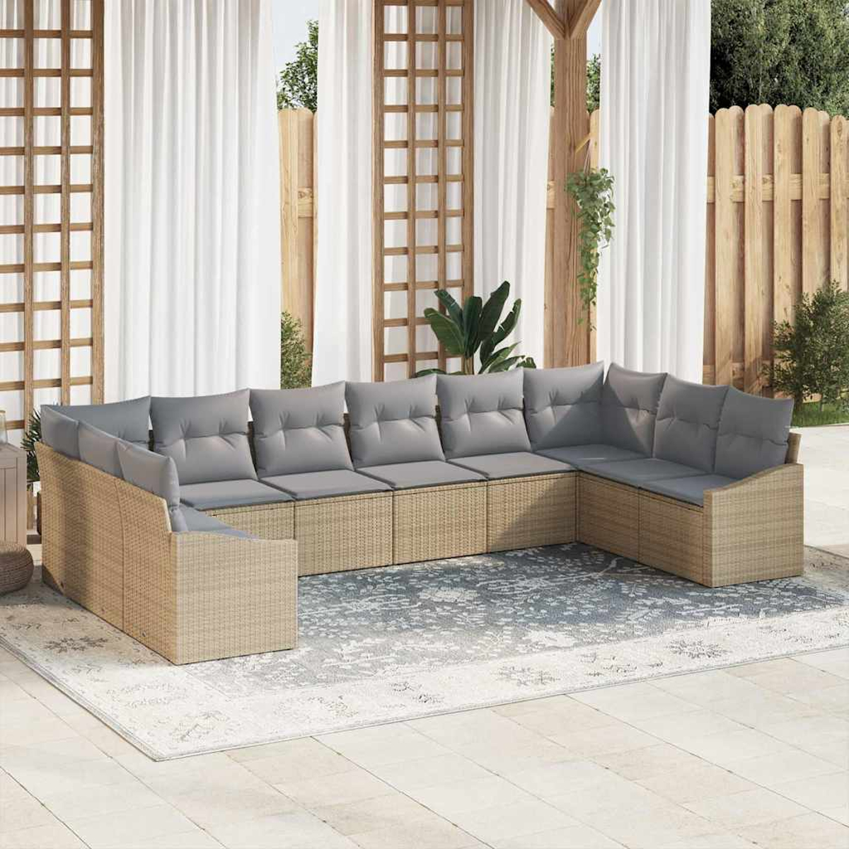 Ein großes, modulares Outdoor-Sofa mit grauen Kissen steht auf einem gemusterten Teppich. Die Szene ist eine Außenterrasse mit Vorhängen und Holzzäunen.