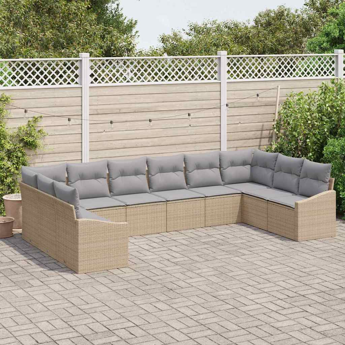 Beige Rattan-Ecksofa mit grauen Kissen auf einer Terrasse. Weißer Gitterzaun und Grün im Hintergrund.