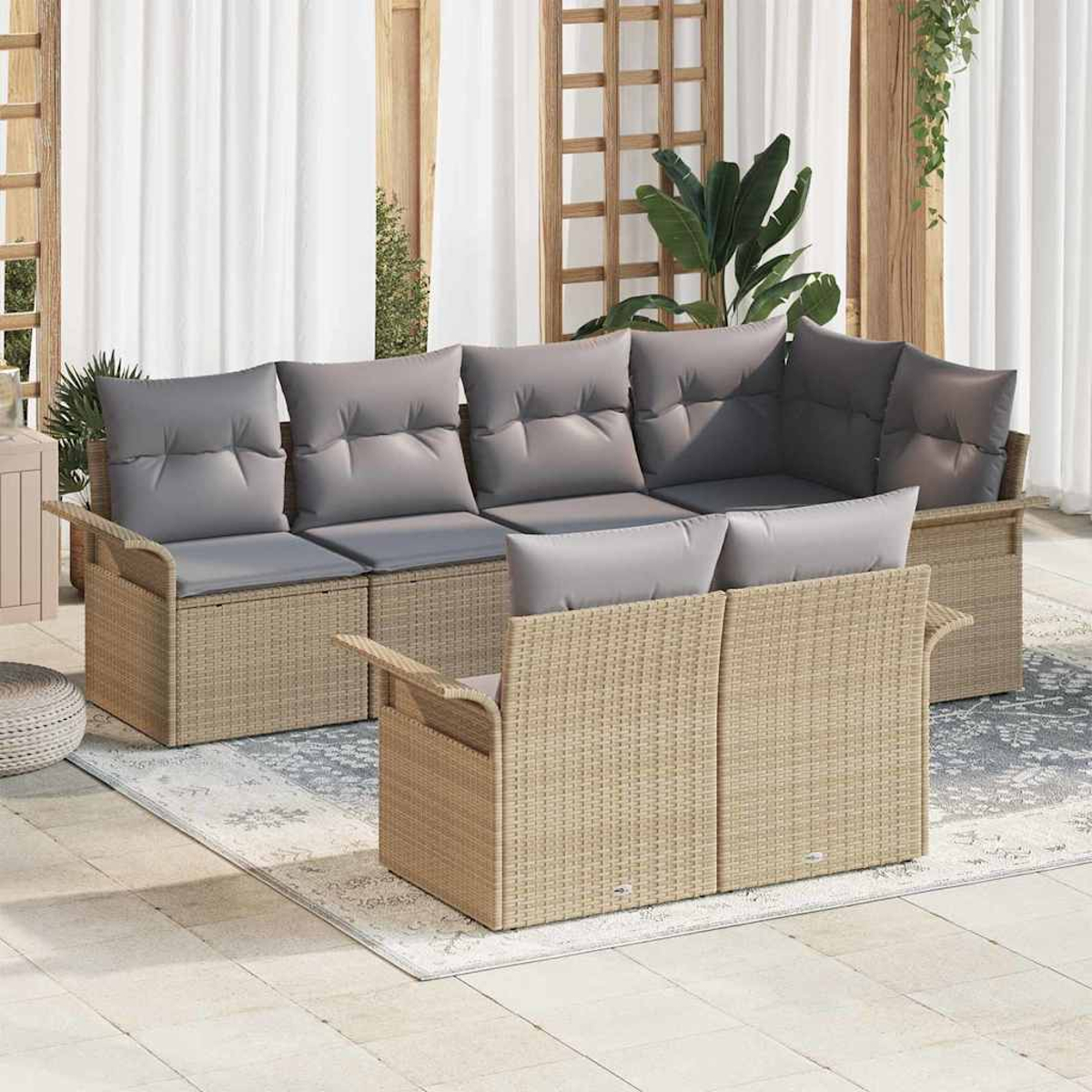 Geflochtenes Outdoor-Sitzgarnitur mit grauen Kissen. Enthält ein Ecksofa und eine Liebesbank auf einem gemusterten Teppich, in der Nähe weißer Vorhänge.