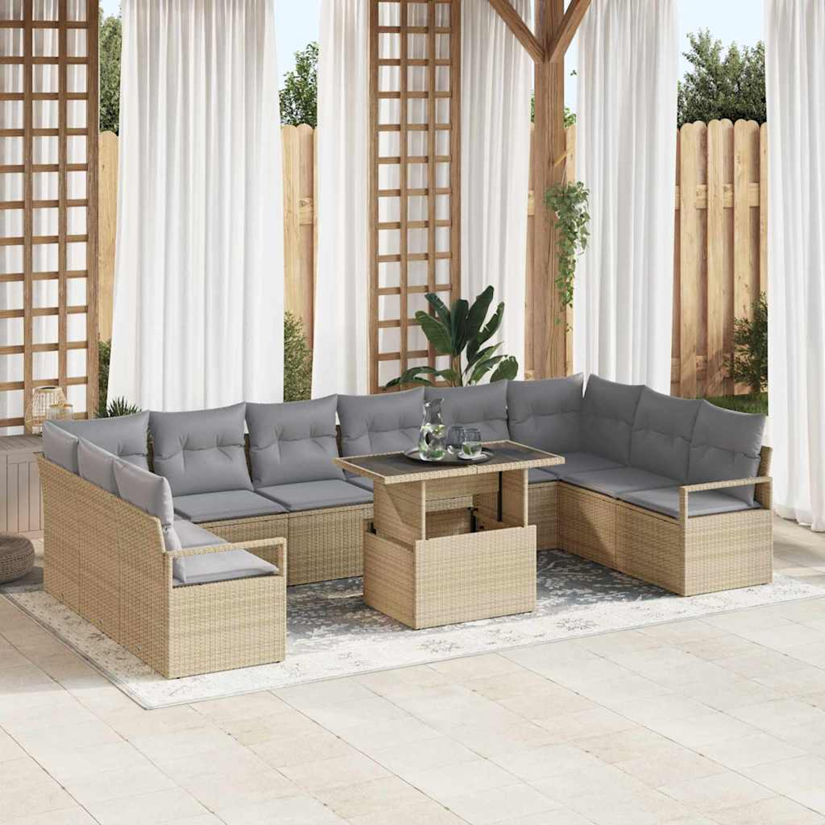 Outdoor-Korbsitzgruppe mit grauen Kissen und einem Tisch, auf einer Terrasse mit weißen Vorhängen und einem Holzzaun.