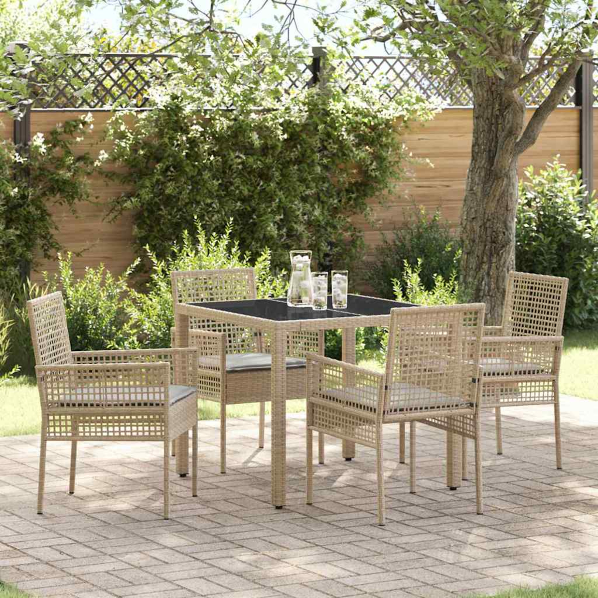 Ein Terrassenset mit quadratischem Tisch und vier Stühlen. Gläser und eine Wasserkaraffe stehen auf dem Tisch. Ein Baum und Laub sind im Hintergrund.