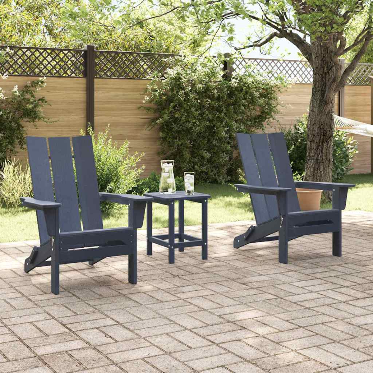 Zwei blaue Adirondack-Stühle und ein kleiner Tisch auf einer Ziegelterrasse. Auf dem Tisch stehen eine Wasserkaraffe und Gläser. Grünes Laub im Hintergrund.