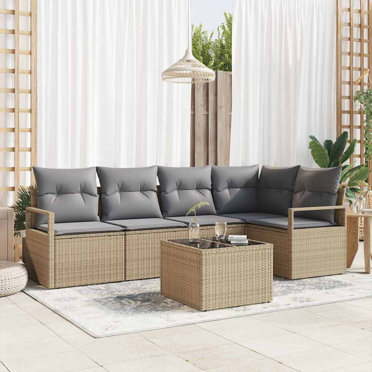 Rattan-Sofa im Freien mit grauen Kissen und einem passenden Couchtisch, auf einer Terrasse mit weißen Vorhängen im Hintergrund.