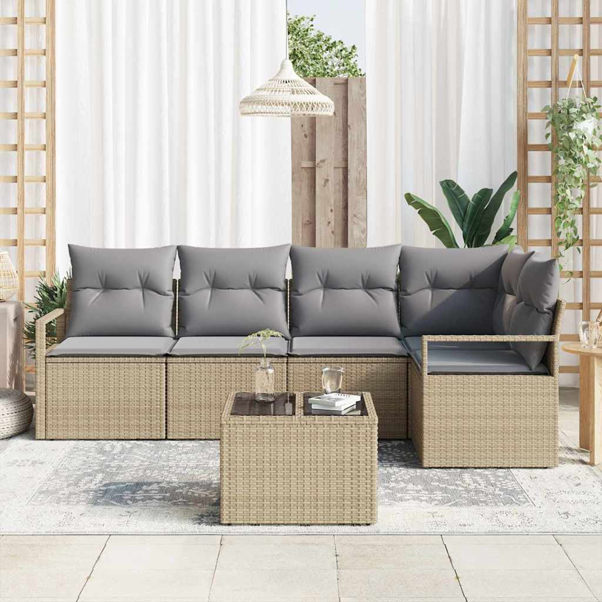 Wohnzimmer im Freien mit Korbsessel, grauen Kissen, Glastisch, weißen Vorhängen, Hängepflanze und dekorativem Licht.