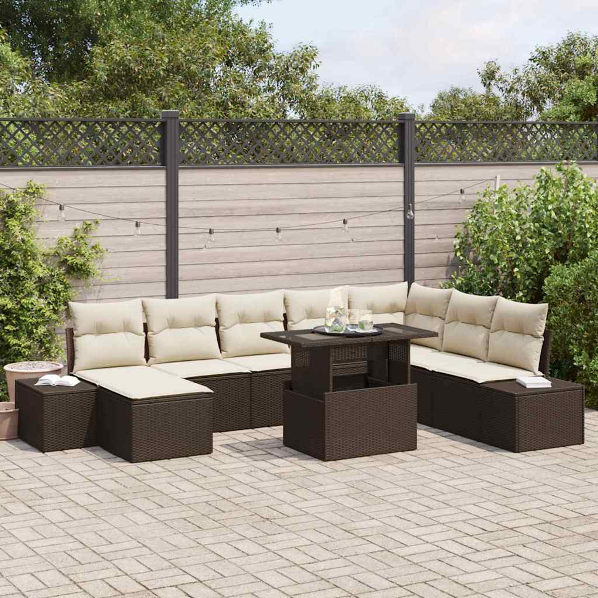 Terrassengarnitur mit braunen Korbmöbeln, beigen Kissen und einem Tisch mit Hubfunktion. Im Hintergrund ein Zaun und Grün.