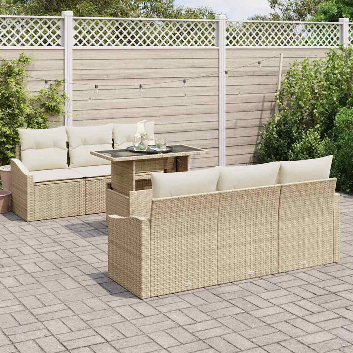 Garten-Terrassenset mit einem Korbmöbel-Sofa, Loveseat und Tisch. Die Szene spielt sich vor einem Holzzaun und üppigem Grün ab.
