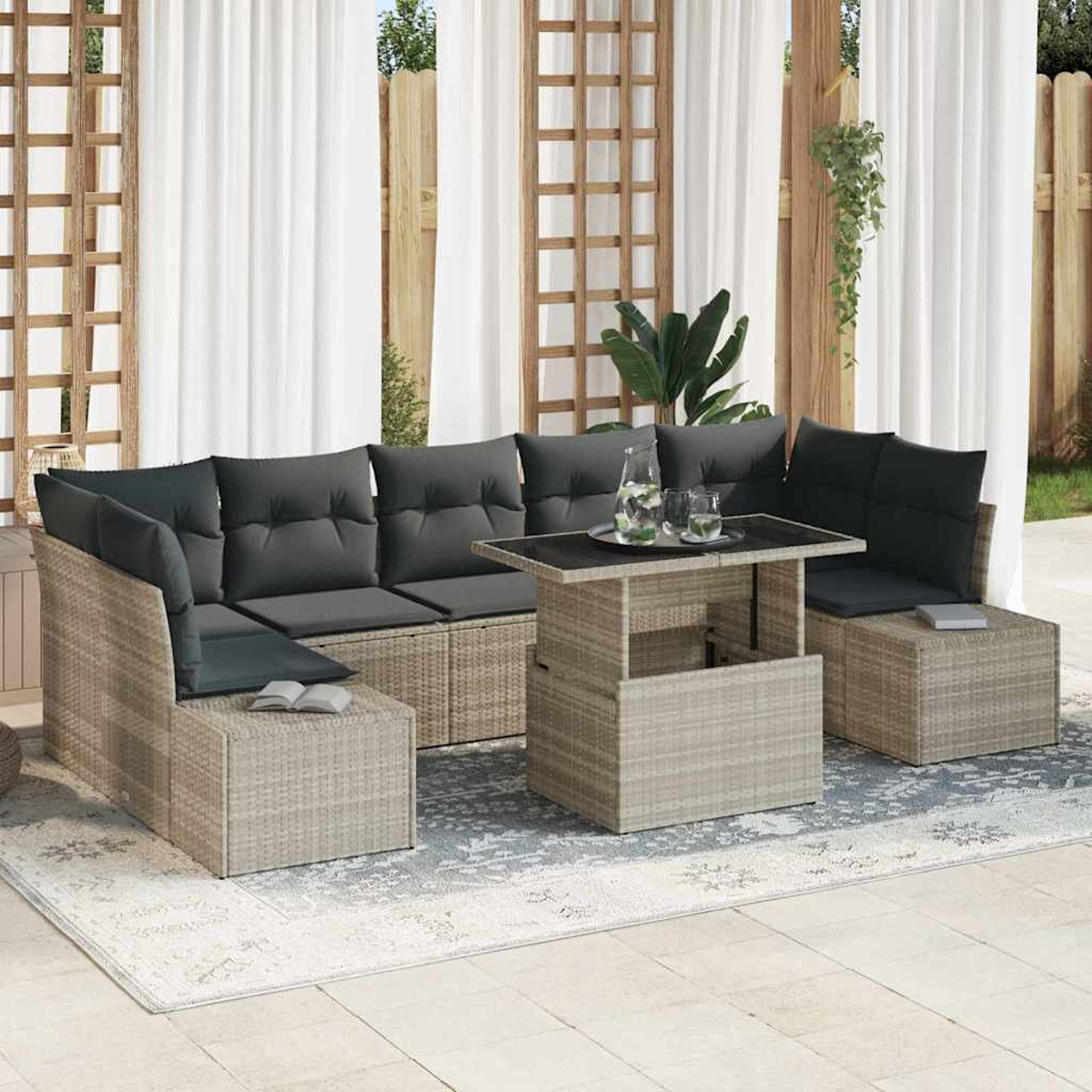Outdoor-Korbmöbel-Set mit grauen Kissen. Ein Couchtisch mit Glas und ein Teppich befinden sich vor weißen Vorhängen.