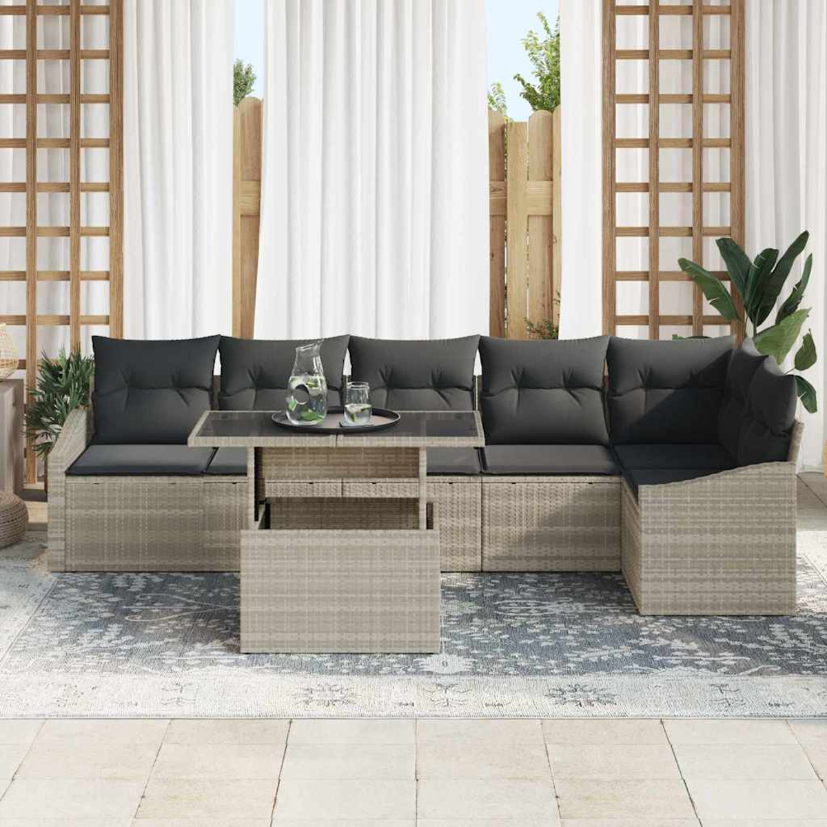 Outdoor-Ecksofa mit grauen Kissen und einem Tisch. Dahinter weiße Vorhänge und ein Holzzaun. Ein Teppich und Pflanzen sind ebenfalls vorhanden.
