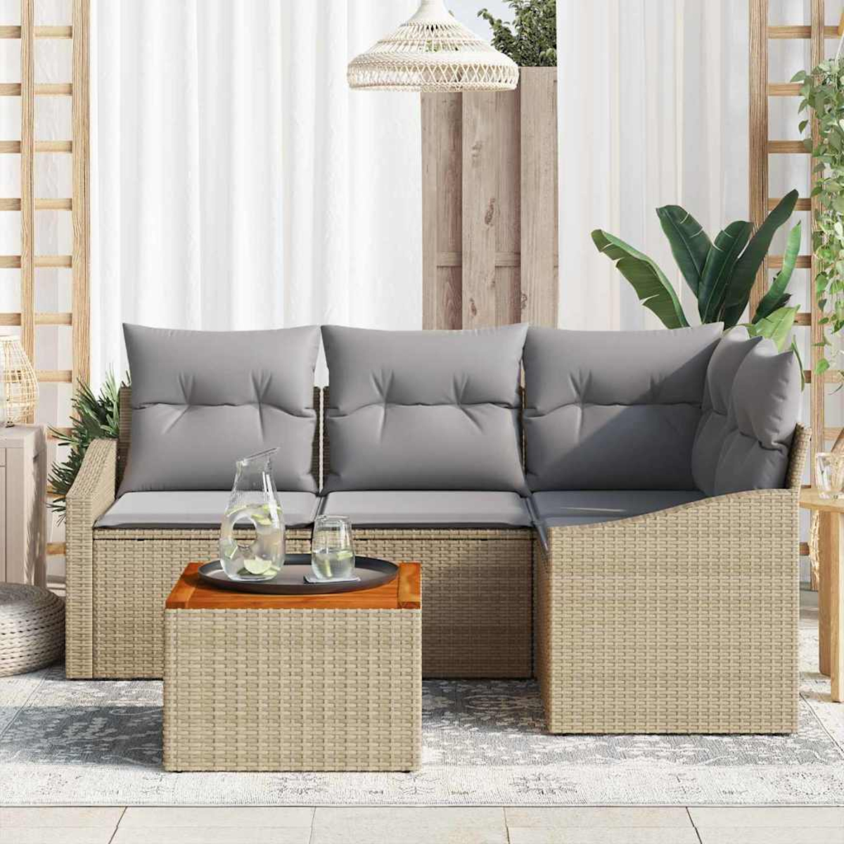 Geflochtenes Outdoor-Ecksofa mit grauen Kissen, Couchtisch mit Getränken. Weiße Vorhänge, Hängelampe und Pflanzen im Hintergrund.