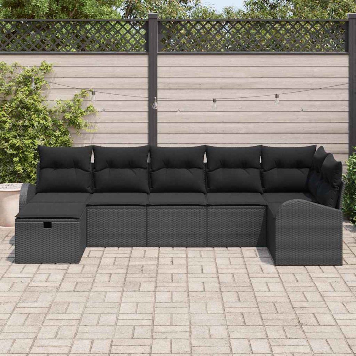 Ein schwarzes Outdoor-Ecksofa mit Kissen steht auf einer Terrasse. Ein Holzzaun und Grünzeug sind im Hintergrund.