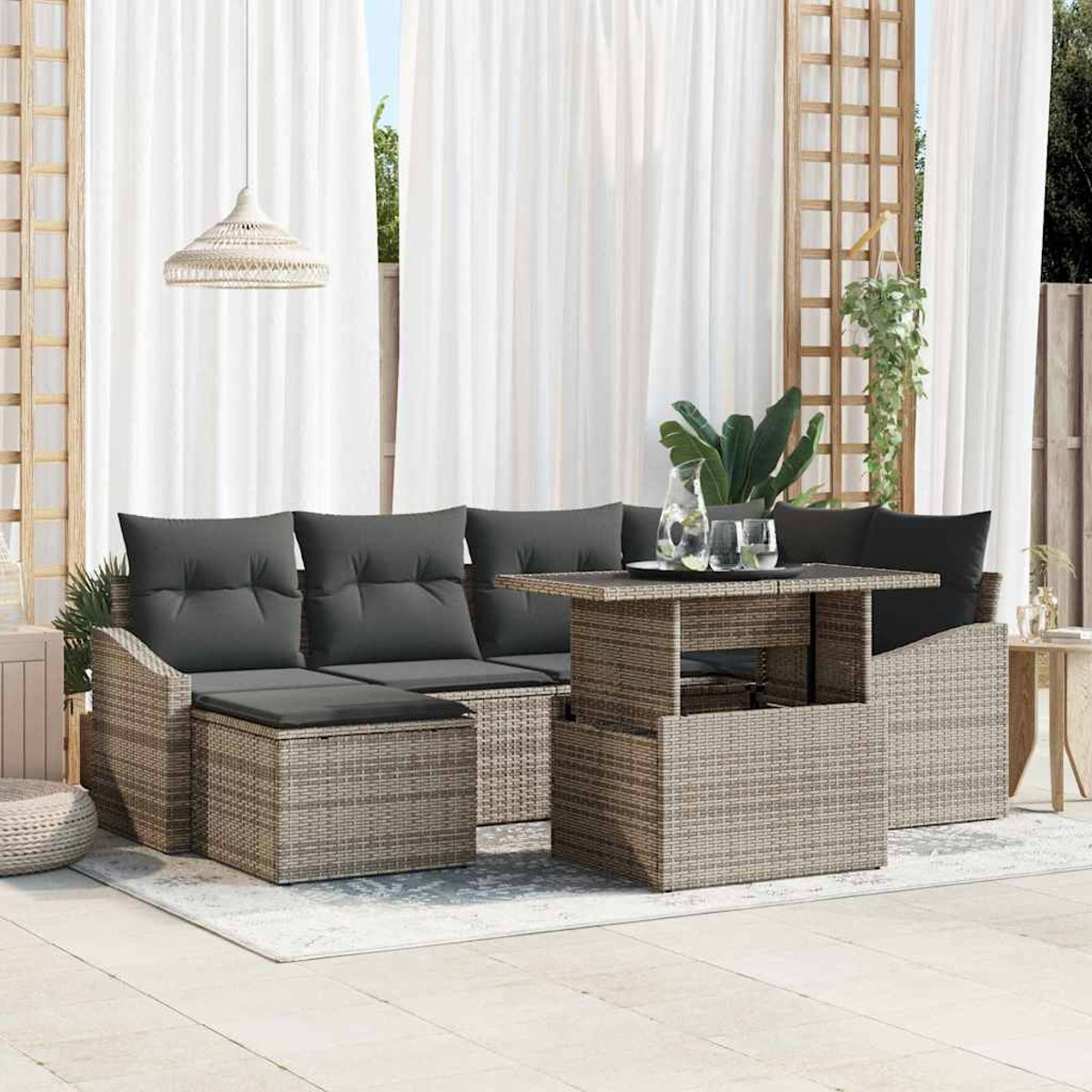 Garten-Sitzgruppe mit grauen Kissen, einem Tisch mit Gläsern und einer Hängelampe. Weiße Vorhänge und ein Holzgitter im Hintergrund.