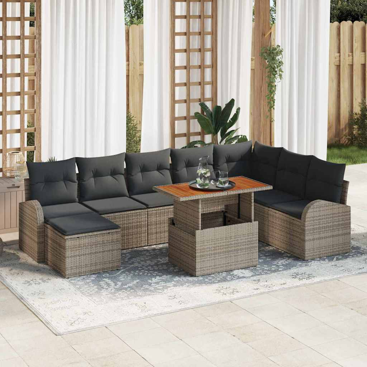 Garten-Rattansofa-Set mit grauen Kissen, Holztisch und weißen Vorhängen. Enthält Teppich, Pflanzen und Holzzaun.