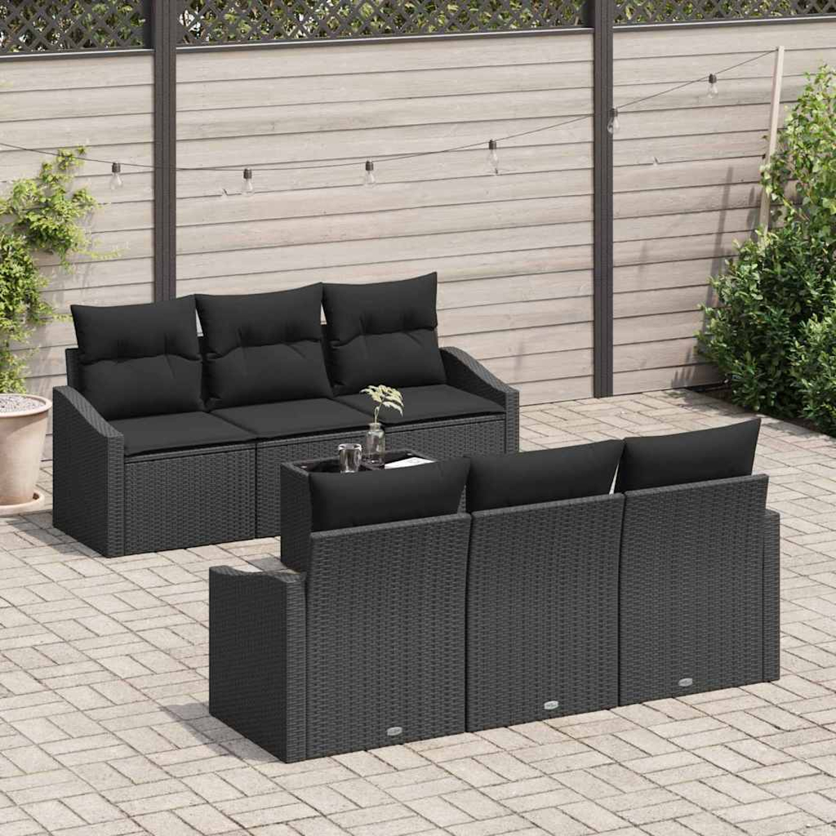Gartenmöbel-Set mit schwarzen Kissen. Ein Tisch mit Gläsern und Blumen steht zwischen zwei Sofas. Im Hintergrund befindet sich ein Zaun.