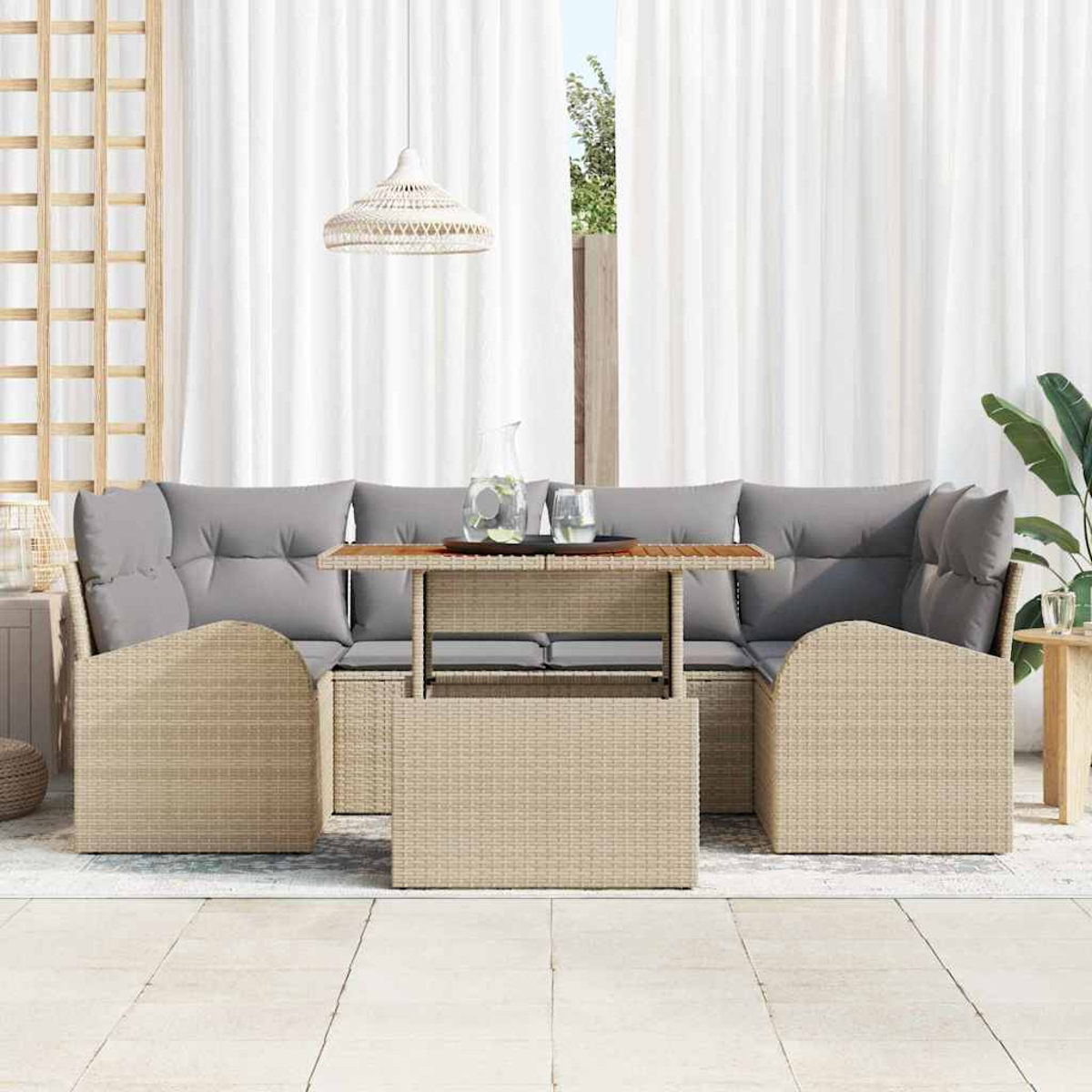 Gartenmöbel-Set aus Korbgeflecht mit grauen Kissen, einem Tisch und einer Hängelampe. Weiße Vorhänge und ein Fenster im Hintergrund.